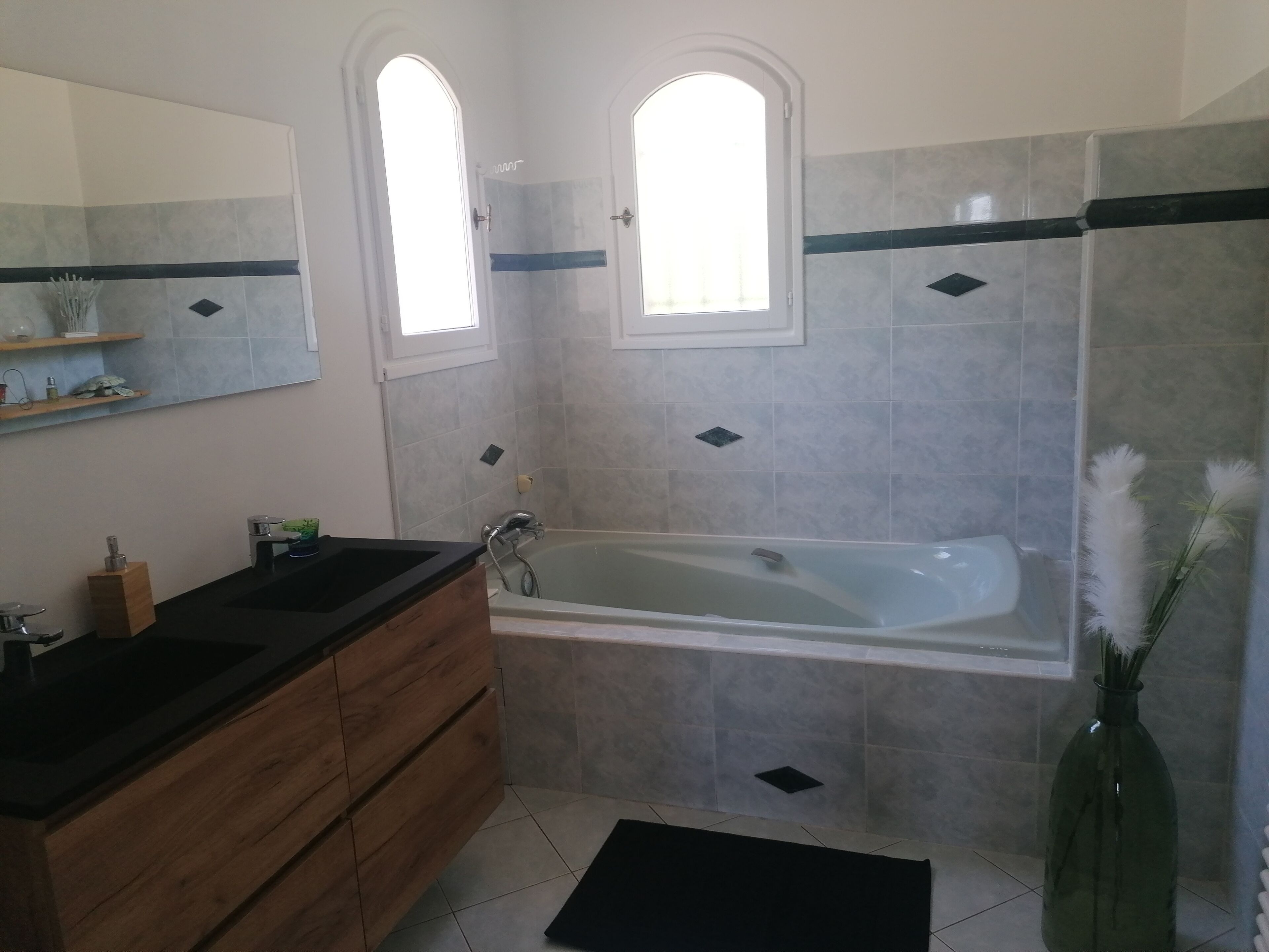 A bathroom with a bathtub, vanity, and a mirror.