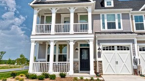 A two-story residential building with a front porch, a garage, and a small attached garage.