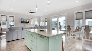 Een moderne keuken met een centraal eiland, een grijze bank en witte kastjes.