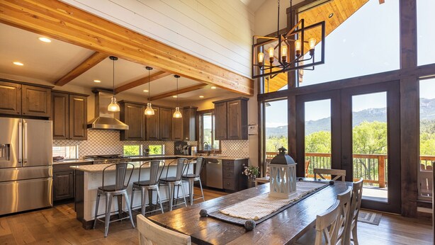 Una cocina amplia con una isla grande, vigas de madera en el techo y vistas al exterior.