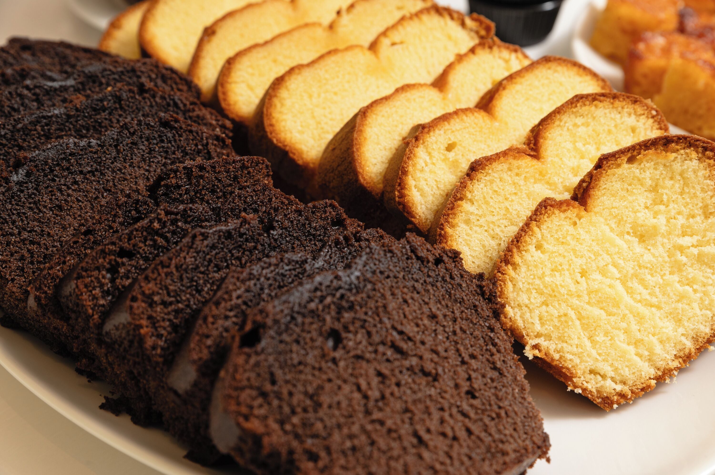 Un plato con rebanadas de pastel de chocolate y pastel de esponja amarillo.