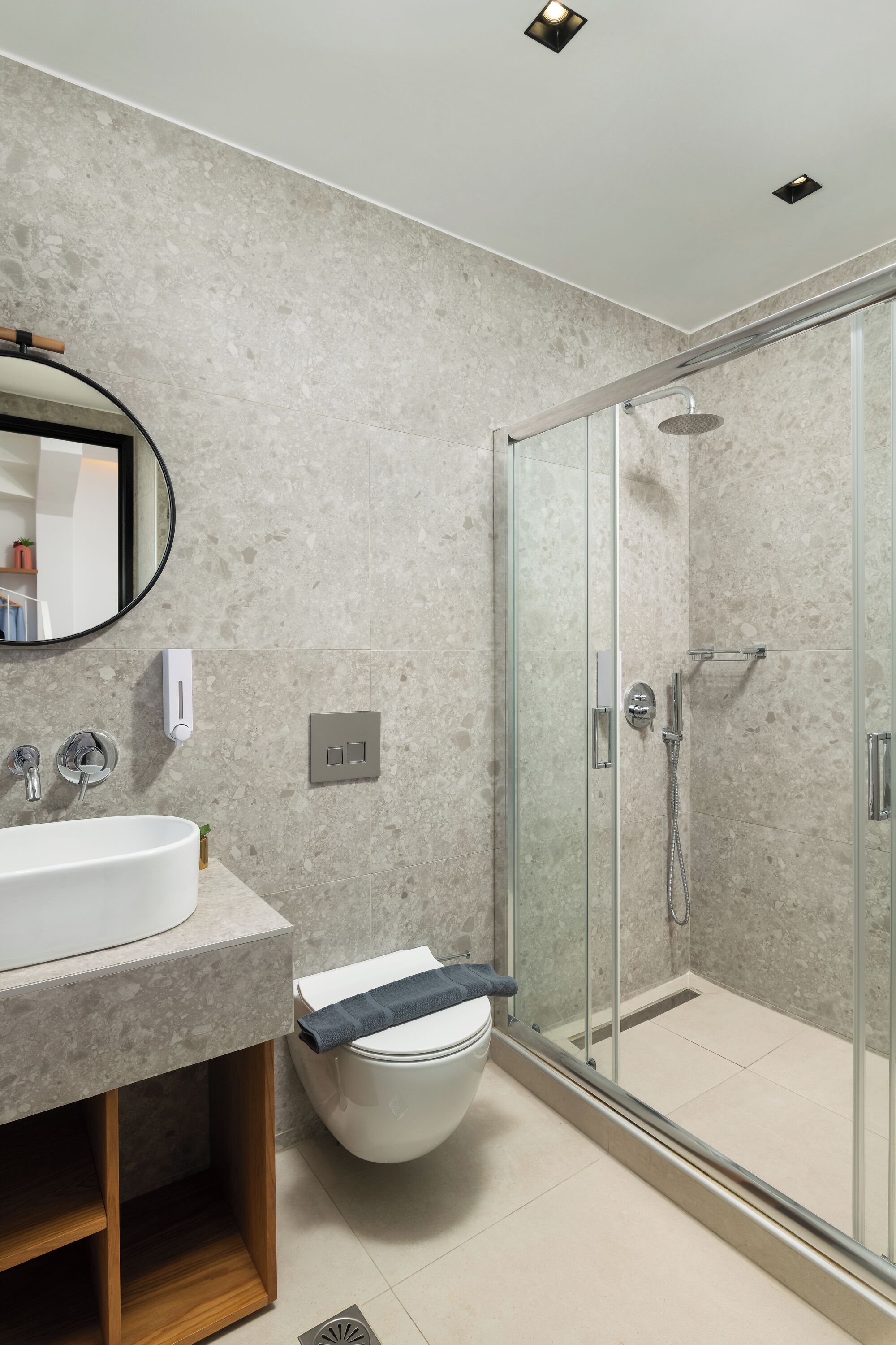 A modern bathroom with a glass shower enclosure, a sink with a mirror, and a toilet.