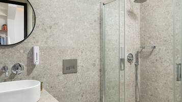 A modern bathroom with a glass shower enclosure, a sink with a mirror, and a toilet.