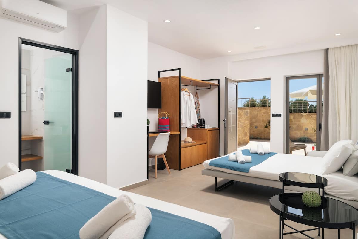 Ein modernes Hotelzimmer mit zwei Betten, einem Schreibtisch, einem Sessel und einem Balkon mit Blick.