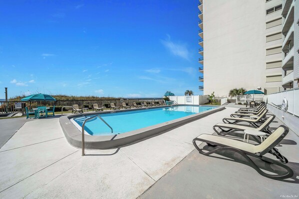 Relax by the rectangular pool surrounded by lounge chairs and tables.