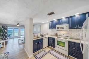 Enjoy meals in this kitchen with a large island, white stove, and ocean views through large windows.