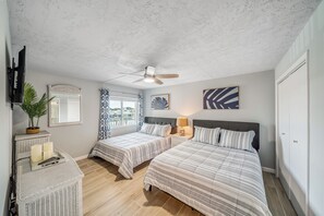 A bedroom with two beds, a ceiling fan, a TV, and a window with curtains. - FREE Golf & Perks! Updated Mariner West 406, Swimming Pool, Tennis & Grills! (Panama City Beach)