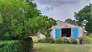 A small brick building with a blue shuttered entrance, surrounded by greenery and a well-maintained lawn. - Calme en Vendée Près de Tout, Idéales Vacances ! (La Garnache)