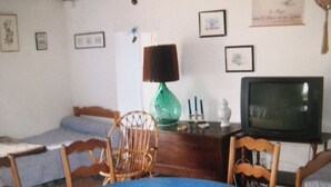 A room with a blue table, a television, a green lamp, and a wooden chair. - Calme en Vendée Près de Tout, Idéales Vacances ! (La Garnache)