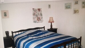 A bedroom with a bed, a nightstand, a lamp, and a wall with pictures. - Calme en Vendée Près de Tout, Idéales Vacances ! (La Garnache)