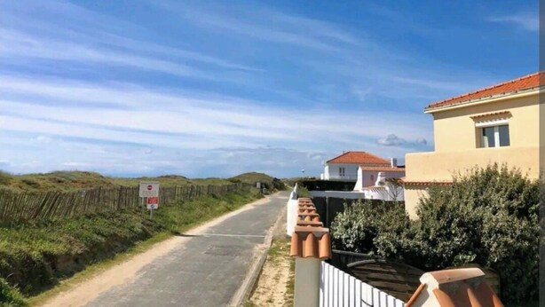 A road with houses on one side and a fence on the other. - Appartement 8/10 Personnes Face à la mer (Barbâtre)