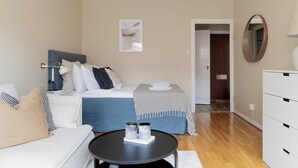 A modern bedroom with a bed, bedside table, and a mirror. - Cozy one room apartment in Stockholm (Stockholm)