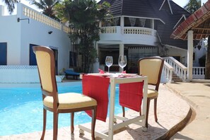 Ein Essbereich am Pool mit zwei Stühlen und einem Tisch, einer roten Tischdecke und zwei Weingläsern.