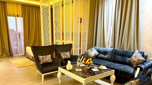 A living room with a black sofa, a black armchair, and a glass coffee table with fruit and a vase. - Z Hotel Meknes (Majjate)