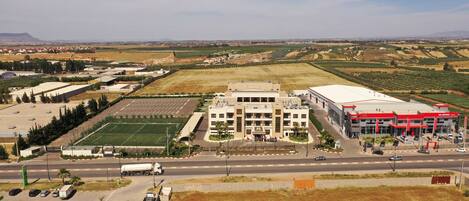 A hotel with a parking lot, a sports field, and a KIA Motors dealership.