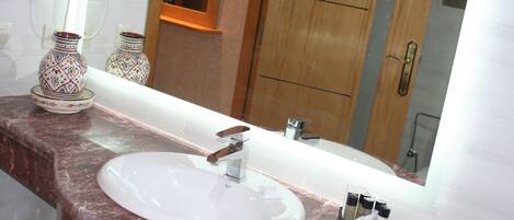 A bathroom with a marble sink, a mirror, and two decorative vases.