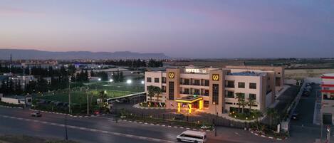 A hotel with a prominent sign, a parking lot, and a view of the surrounding area.