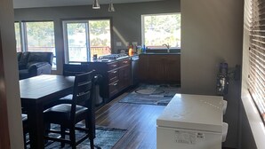 Uma cozinha moderna com armários de madeira, uma área de refeições com mesa e cadeiras, e uma geladeira embutida.