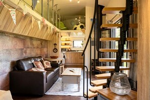 Un salon moderne avec un canapé, une table basse et un escalier doté d’une rampe en bois.