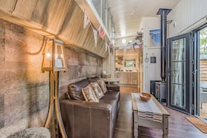 A cozy living room with a leather sofa, a wooden coffee table, and a rustic wall.