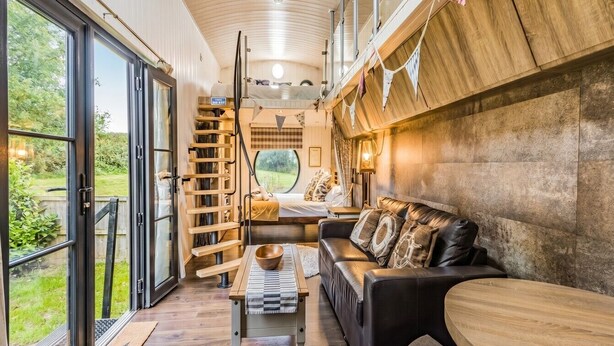 A modern interior with a wooden bench, a sofa, and a dining table. - Two-Level Shepherd`s Hut · Sleeps 4 with Kids` Den · Fire Pit near Dartmouth (Dartmouth)