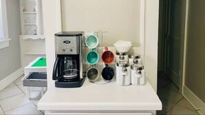Un coin café équipé d’une machine à café, de tasses et d’un moulin à café.