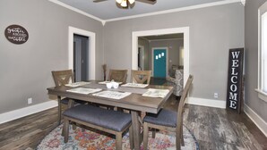 Un coin repas avec une table en bois, des chaises et un ventilateur de plafond.