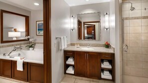 Une salle de bain équipée d’une baignoire, d’un lavabo, d’une douche et d’un meuble-lavabo avec des placards de rangement.