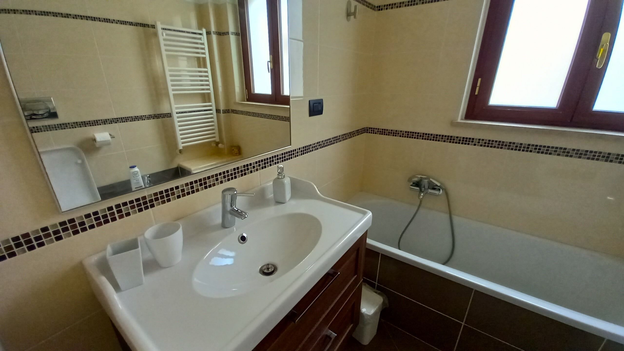 A bathroom with a white sink, a mirror, a towel rack, and a bathtub.