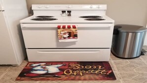 Une cuisine avec un four blanc, une poubelle et un panneau mural sur lequel est écrit « Mangez ».