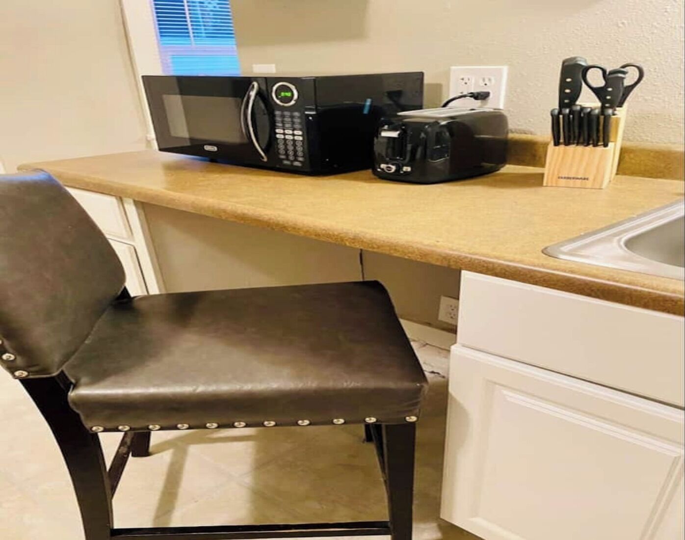 A kitchen with a microwave, toaster, and knife set on the counter.