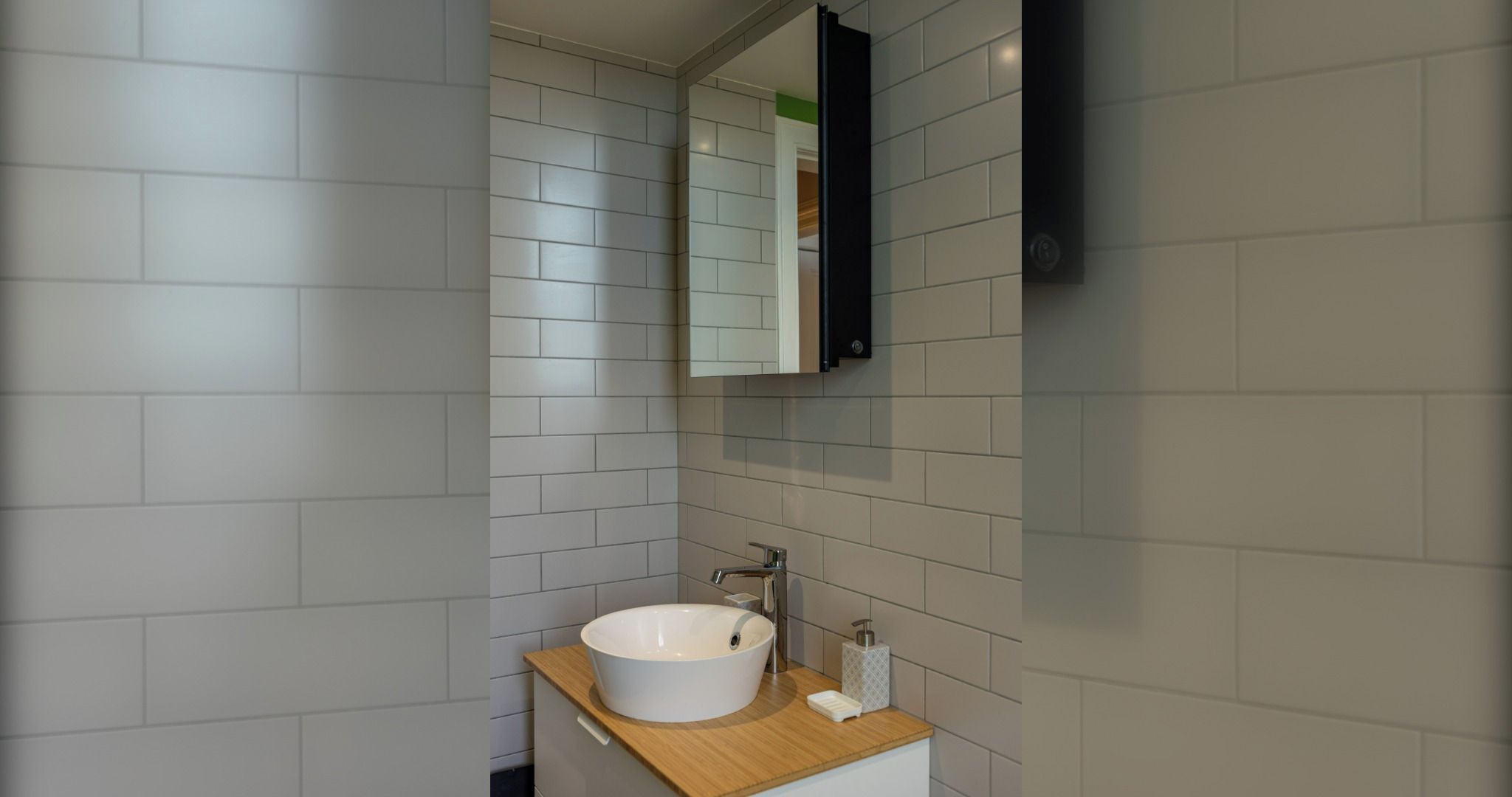 Ein Badezimmer mit einem weißen Waschbecken, einem Spiegel und einer Holzablage.