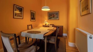A dining room with a table set for four, framed artwork on the walls, and a hanging light fixture. - Newly renovated 1BDR APT near charming Newhaven (Edinburgh)