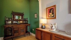 A room with a green wall, wooden furniture, a lamp, and a framed picture. - Newly renovated 1BDR APT near charming Newhaven (Edinburgh)