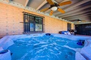 A hot tub with a brick wall and a ceiling fan.