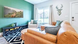 Ein Wohnzimmer mit einer Couch, einem Couchtisch, einem Fernseher und einem Bild von einem Tier.