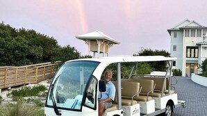 A golf cart parked on a paved area with a house in the background. - KIVA ON THE GULF: PRIVATE BEACH, PREMIER GOLF COURSE, AND 3 POOLS! (Gulf Shores)