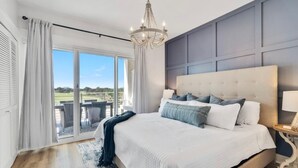 A bedroom with a large bed, a chandelier, a view through the window, and a balcony. - KIVA ON THE GULF: PRIVATE BEACH, PREMIER GOLF COURSE, AND 3 POOLS! (Gulf Shores)