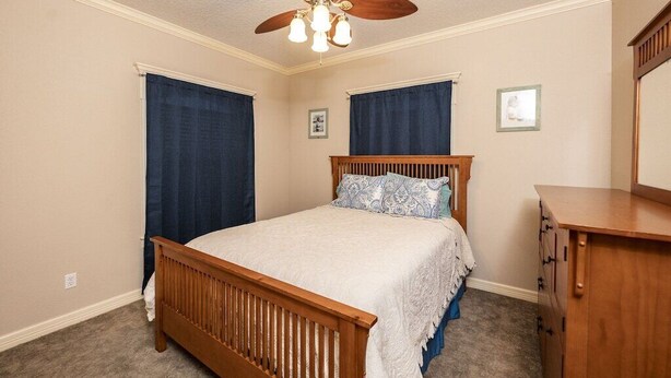 A bedroom with a wooden bed, a ceiling fan, and a dresser.