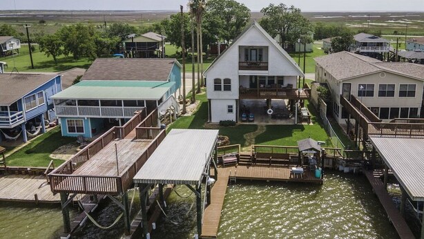 A waterfront property with a main house, a dock, and several smaller buildings. - Riverfront Home w/ Fishing Pier, Minutes to Beach (Matagorda)