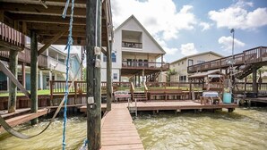 A wooden dock leading to a house with a balcony, surrounded by water. - Riverfront Home w/ Fishing Pier, Minutes to Beach (Matagorda)