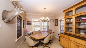A dining room with a large wooden table, chairs, a chandelier, and a mounted deer head on the wall. - Riverfront Home w/ Fishing Pier, Minutes to Beach (Matagorda)