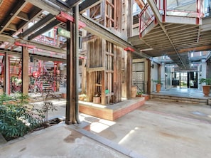 A spacious atrium with high ceilings, wooden beams, and a central staircase. - Heritage Woolstore Apartment | Teneriffe, Brisbane (Teneriffe)