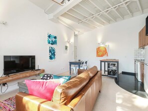A living room with a TV, sofa, and artwork on the walls.