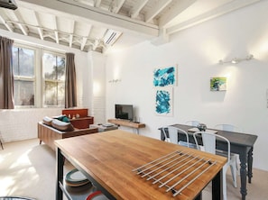 Una sala de estar moderna con una mesa de comedor de madera, un televisor y obras de arte en las paredes.