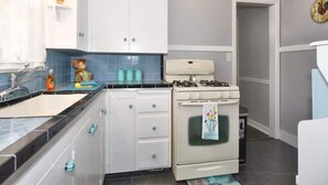 Una cocina con armarios blancos, una estufa y un lavabo.