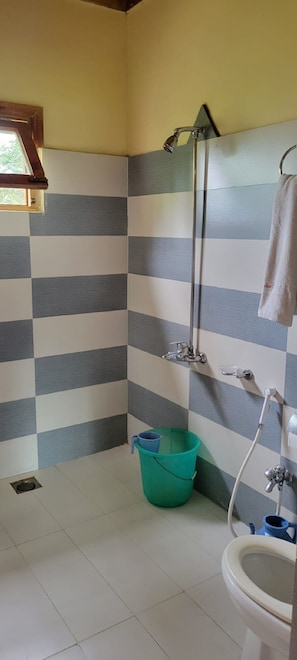 Une salle de bain avec un mur recouvert de carreaux à motifs, une douche, des toilettes et une fenêtre avec un cadre en bois.