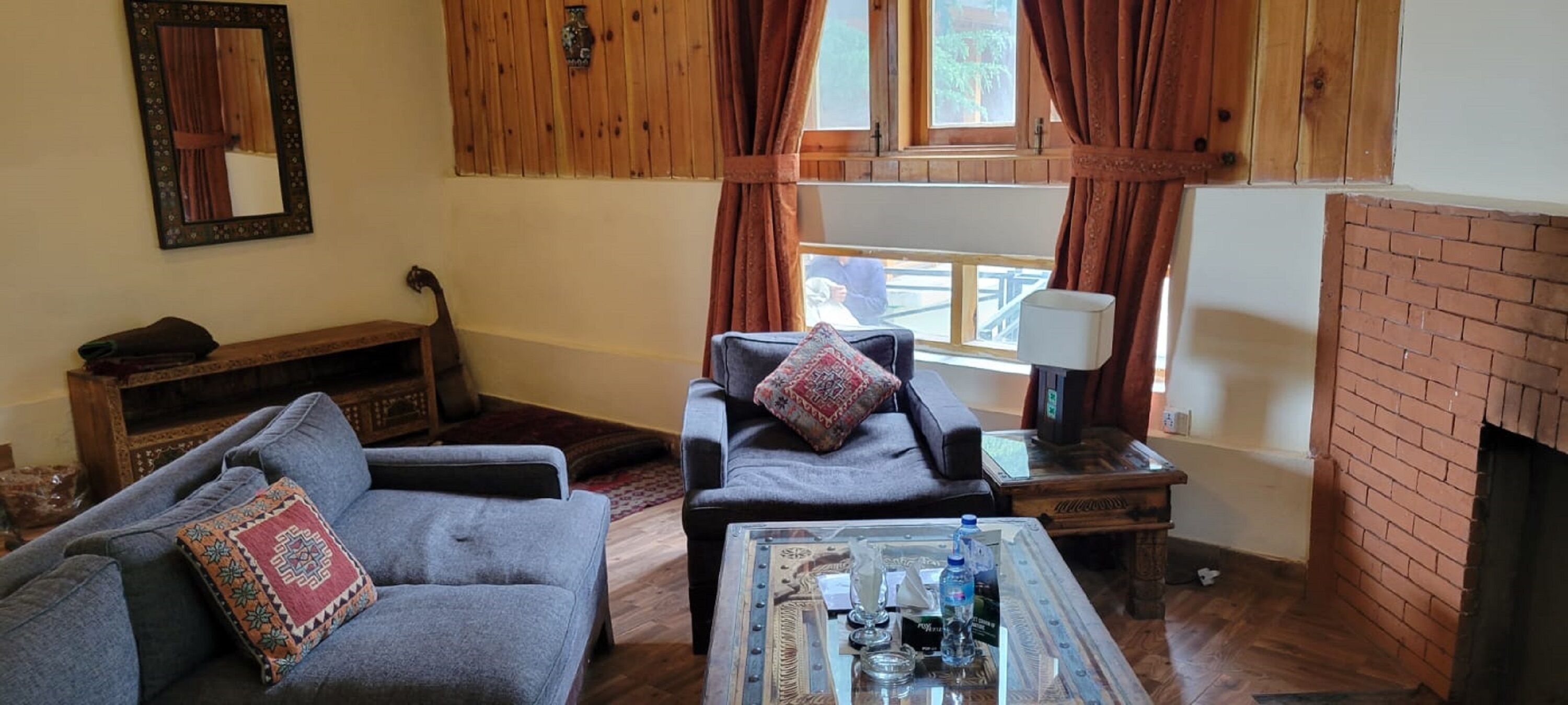 Una sala de estar acogedora con sofá, sillón y mesa de centro, paredes de madera y chimenea.