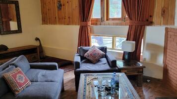 Una sala de estar acogedora con sofá, sillón y mesa de centro, paredes de madera y chimenea.