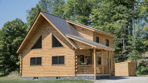A log cabin with a gabled roof, a front porch, and a stone foundation. - Stay on Kingdom Trails in a four bedroom cabin! (Burke)